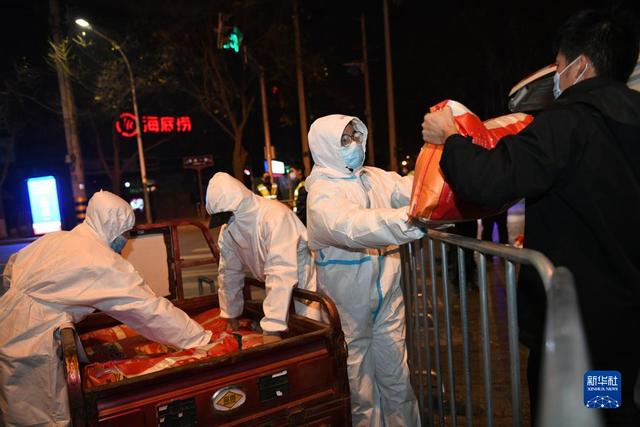 陕西省石油化工学校工作人员在隔离栏处转运大米