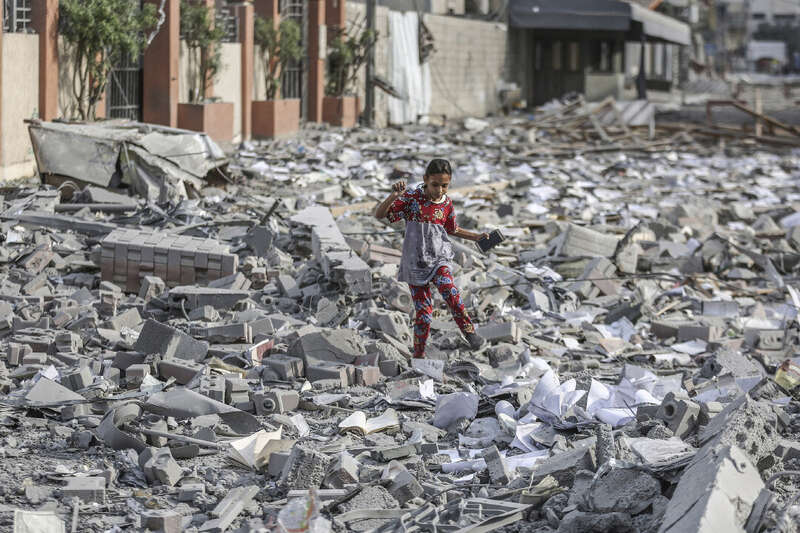 一名巴勒斯坦女孩走在被毁建筑的废墟中